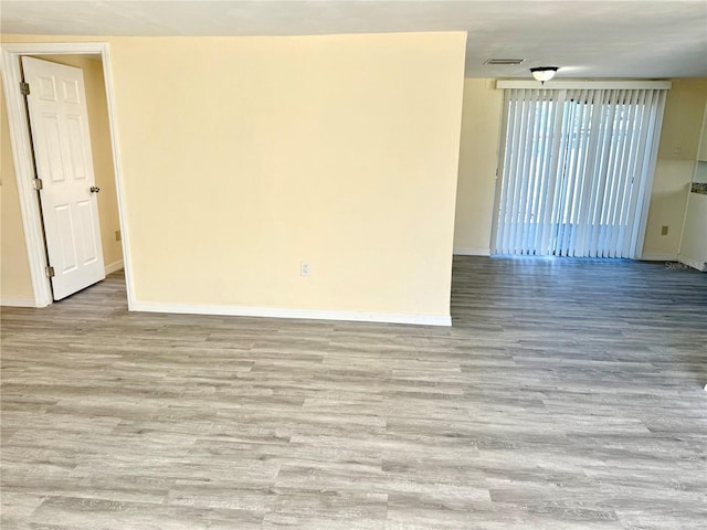 unfurnished room with wood finished floors, visible vents, and baseboards