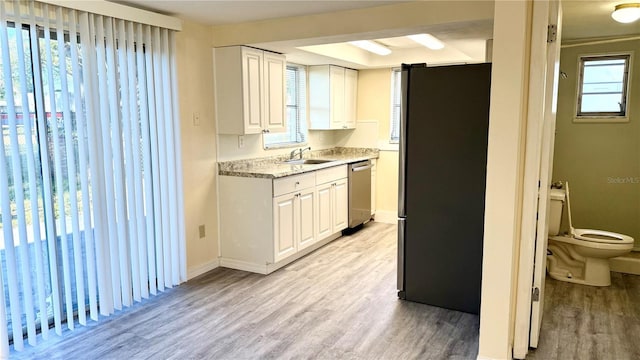 kitchen featuring appliances with stainless steel finishes, light countertops, a sink, and light wood-style flooring