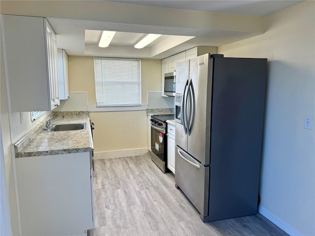 kitchen with light wood finished floors, a raised ceiling, light countertops, stainless steel appliances, and a sink