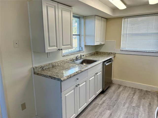 kitchen featuring light wood-style flooring, stainless steel dishwasher, white cabinetry, a sink, and baseboards