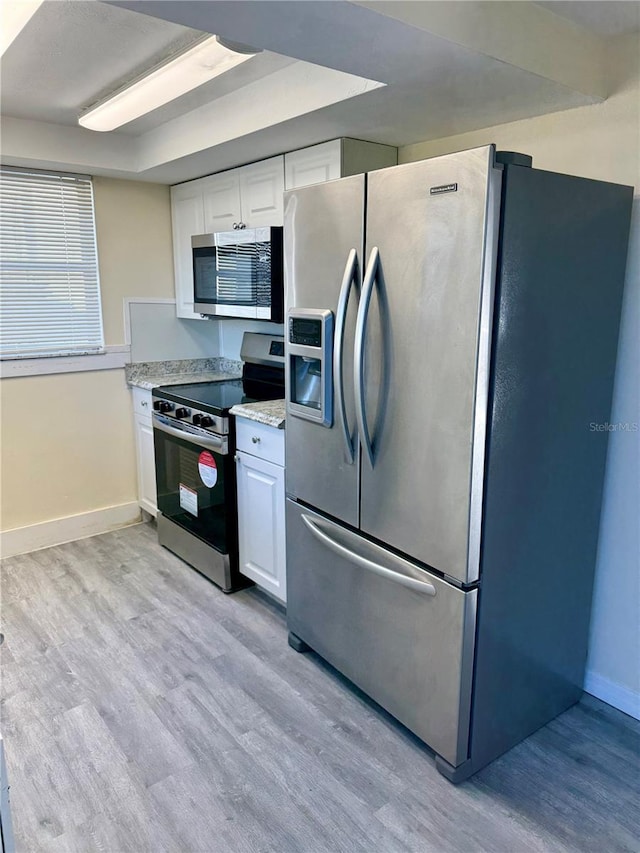 kitchen featuring baseboards, light wood-style flooring, light stone counters, stainless steel appliances, and white cabinetry