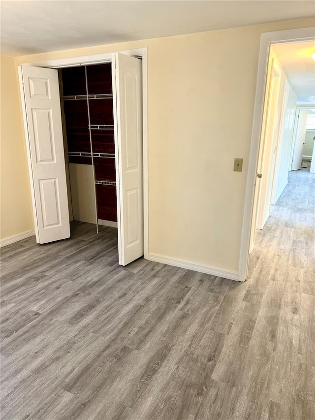 unfurnished bedroom featuring a closet, wood finished floors, and baseboards