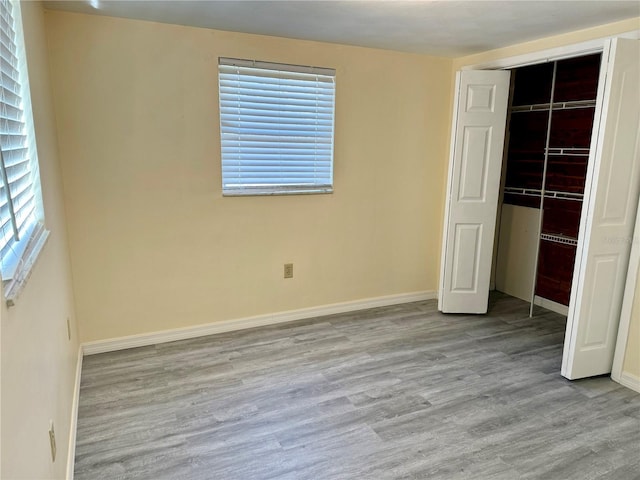 unfurnished bedroom with a closet, wood finished floors, and baseboards