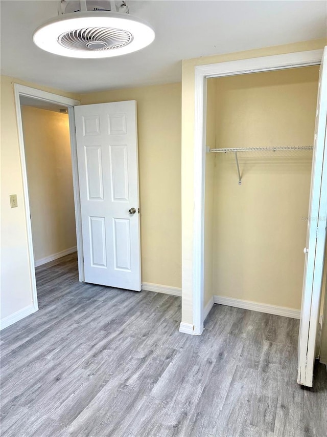 unfurnished bedroom with a closet, visible vents, baseboards, and wood finished floors