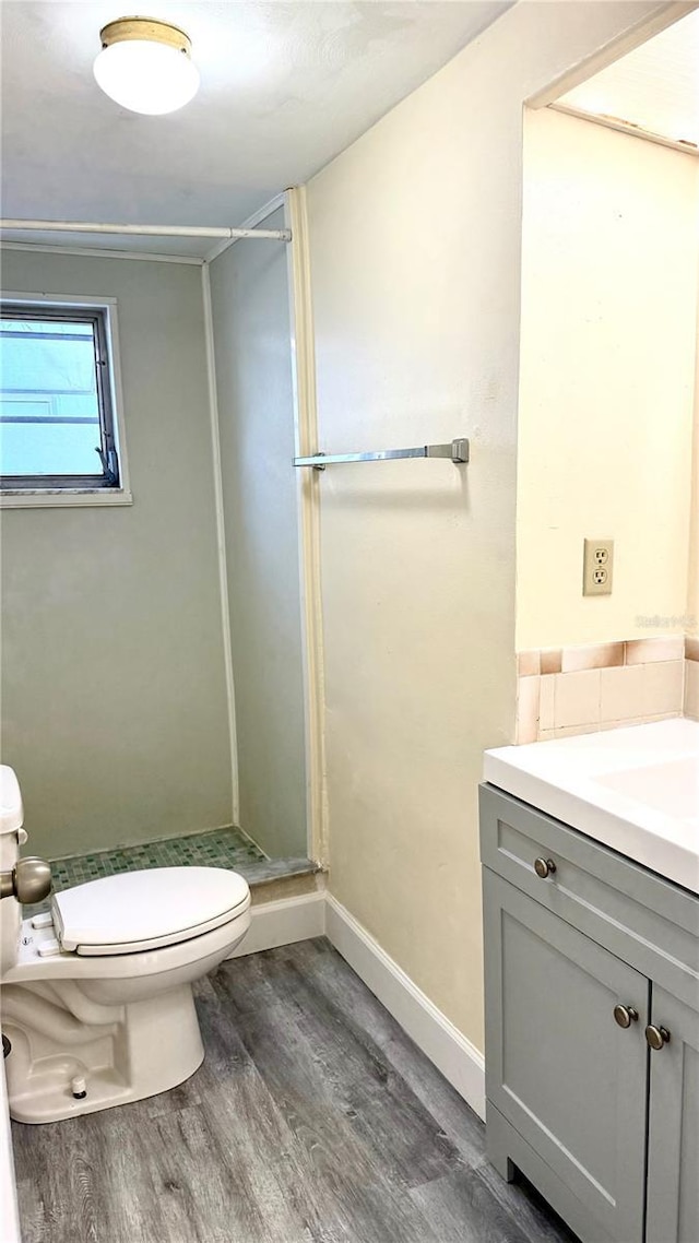 full bathroom featuring toilet, vanity, a shower stall, wood finished floors, and baseboards