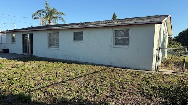 back of property featuring stucco siding, a lawn, and fence