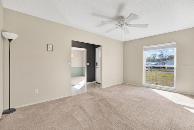 spare room featuring a textured ceiling, a ceiling fan, and light colored carpet