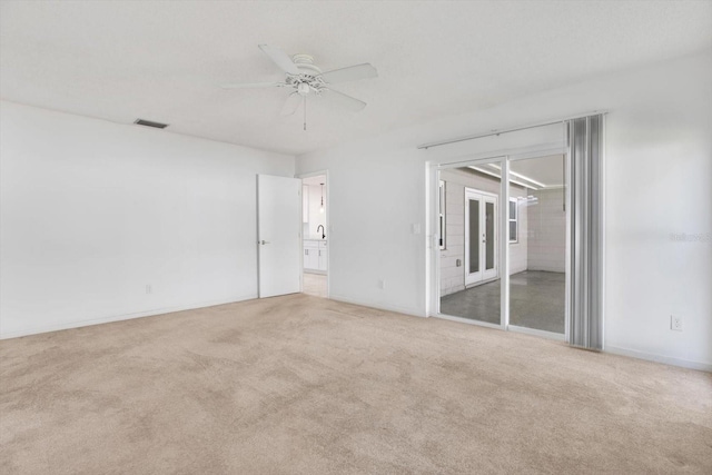 spare room featuring ceiling fan, carpet, and visible vents