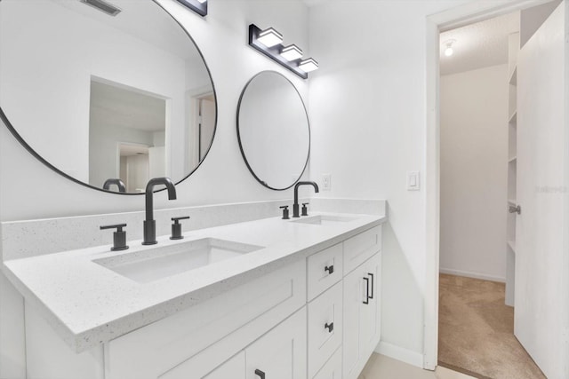 full bath featuring double vanity, baseboards, visible vents, and a sink