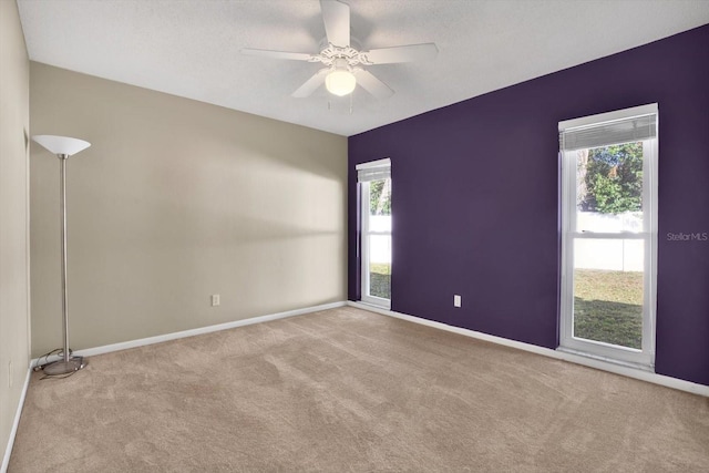 spare room featuring carpet floors, baseboards, and a ceiling fan