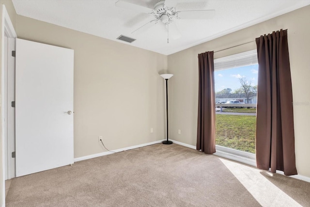 carpeted empty room featuring visible vents and a ceiling fan