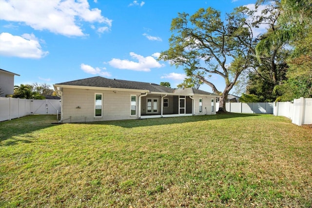 back of property featuring a sunroom, a fenced backyard, and a lawn