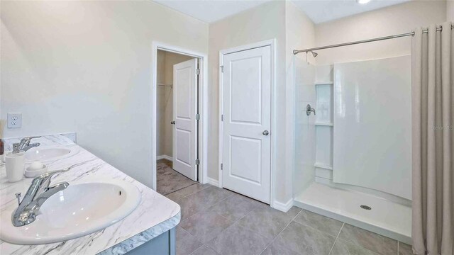 bathroom with double vanity, a stall shower, tile patterned flooring, and a sink