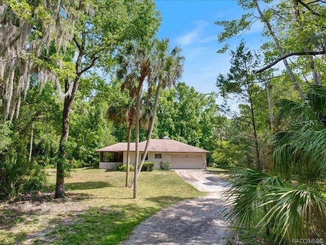 view of front of property with a front lawn, a wooded view, driveway, and an attached garage