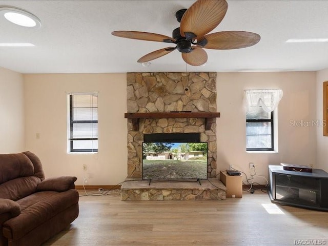 living room featuring ceiling fan, a fireplace, and wood finished floors