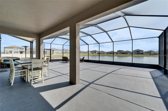 view of patio featuring outdoor dining area, a water view, a residential view, and a lanai