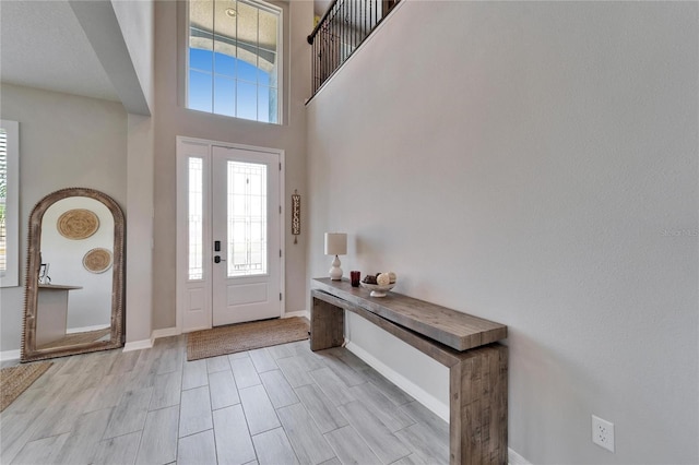 entryway with a high ceiling, baseboards, and wood tiled floor