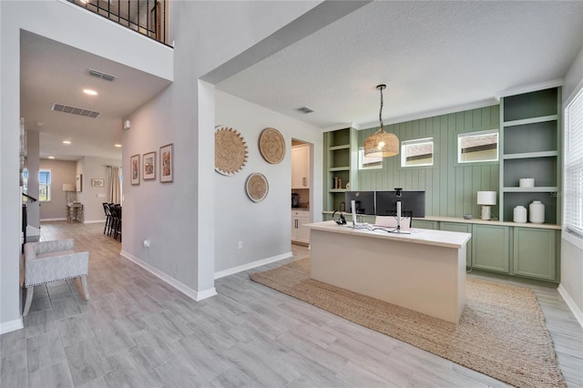 kitchen featuring open shelves, visible vents, green cabinets, and light wood-style flooring