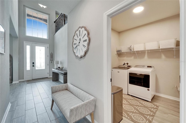 entrance foyer with a high ceiling, light wood-style flooring, washing machine and dryer, and baseboards