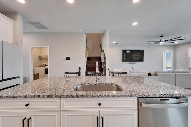 kitchen featuring light stone counters, visible vents, white cabinetry, a sink, and stainless steel dishwasher