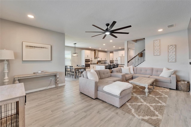 living room with light wood-style flooring, visible vents, and a textured ceiling