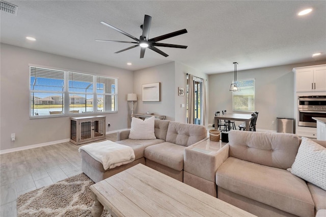 living area with visible vents, baseboards, ceiling fan, recessed lighting, and a textured ceiling