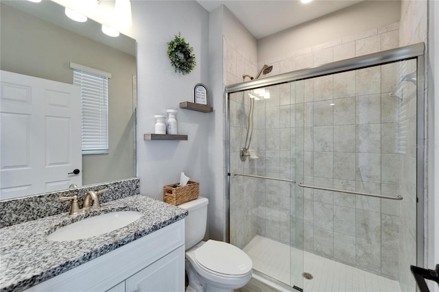 bathroom with vanity, a shower stall, and toilet