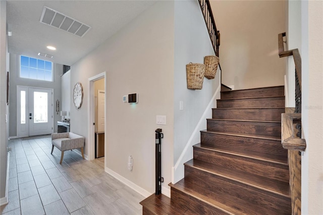 foyer entrance featuring visible vents, stairway, and baseboards