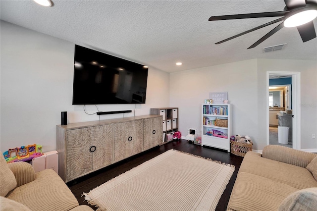 living area featuring visible vents, baseboards, wood finished floors, a textured ceiling, and a ceiling fan