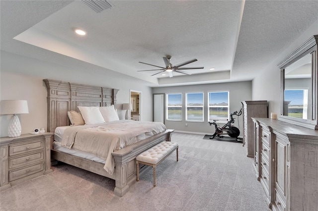 bedroom with visible vents, a textured ceiling, baseboards, a raised ceiling, and light colored carpet