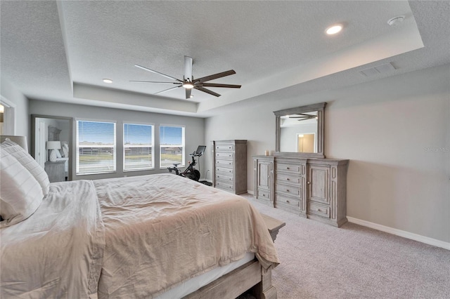 bedroom with ceiling fan, baseboards, light carpet, a textured ceiling, and a raised ceiling