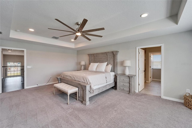 bedroom with a raised ceiling, carpet flooring, and a textured ceiling