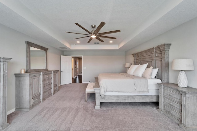 carpeted bedroom with visible vents, a tray ceiling, a textured ceiling, recessed lighting, and baseboards