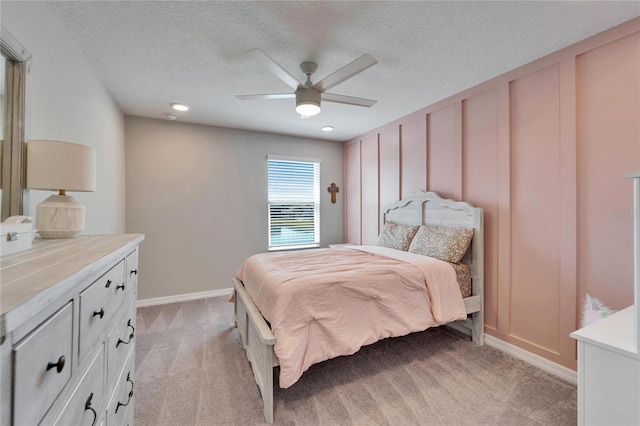 bedroom featuring a textured ceiling, ceiling fan, baseboards, and light carpet