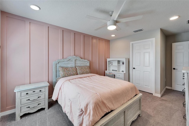 bedroom with a decorative wall, recessed lighting, light colored carpet, and visible vents