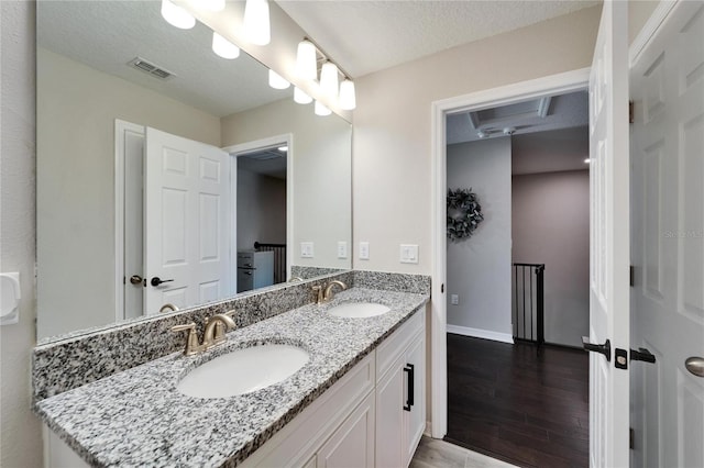 bathroom with a sink, visible vents, a textured ceiling, and double vanity