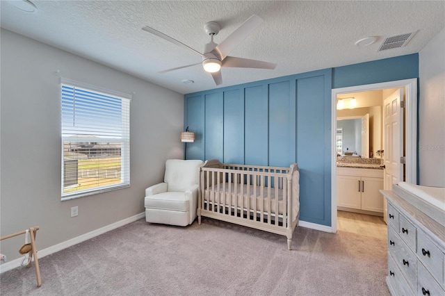 bedroom with visible vents, baseboards, light colored carpet, and a textured ceiling