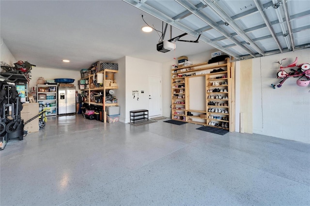 garage featuring a garage door opener and stainless steel refrigerator with ice dispenser