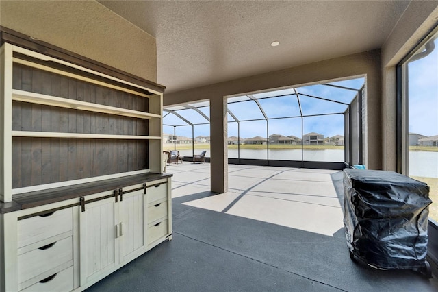 view of patio / terrace featuring glass enclosure and a water view