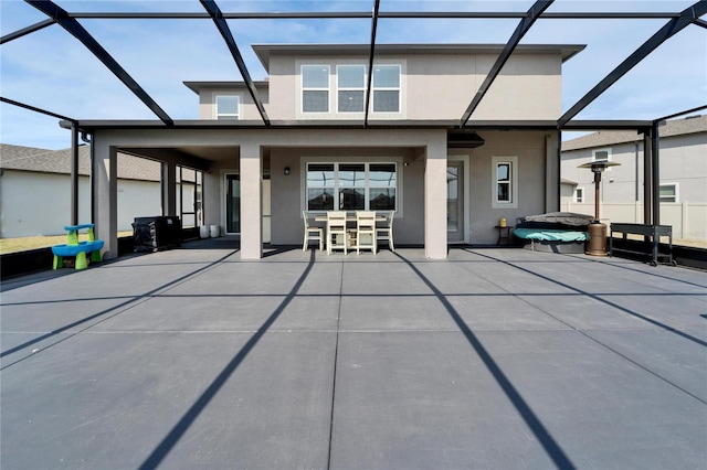 exterior space featuring glass enclosure, a patio area, and stucco siding