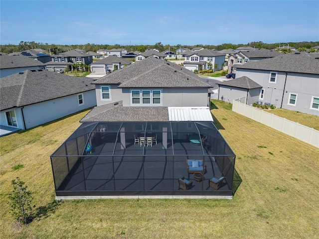 back of property with glass enclosure, a residential view, and a yard