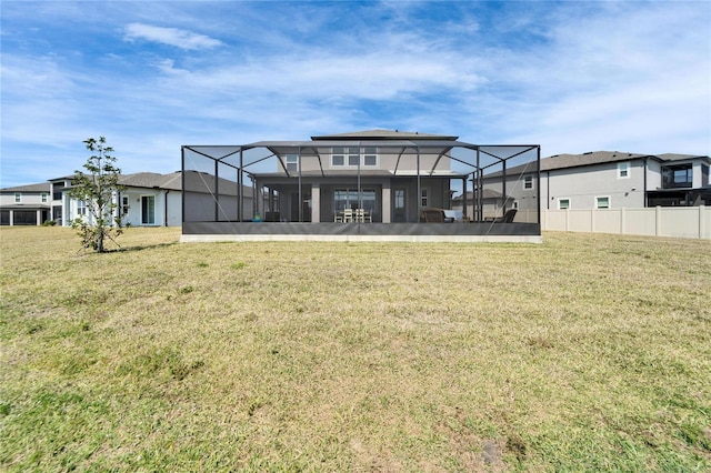 rear view of property with a lanai, a residential view, a yard, and fence