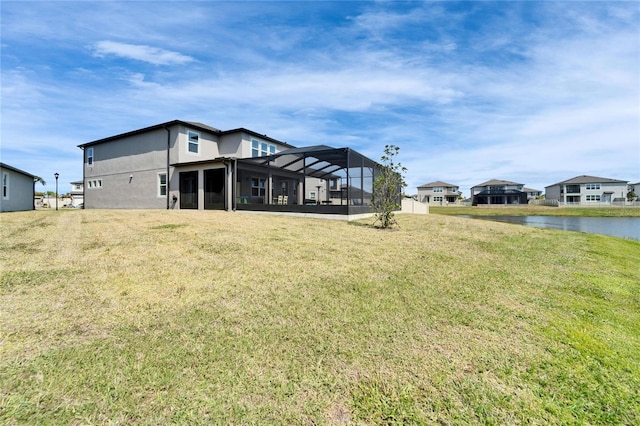 back of house with glass enclosure, a water view, and a lawn