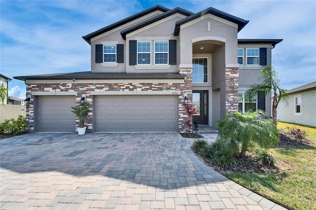 view of front of house featuring stone siding, stucco siding, decorative driveway, and a garage