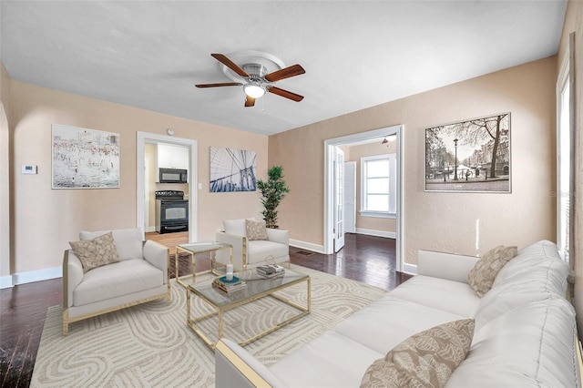 living room with baseboards, wood finished floors, and a ceiling fan