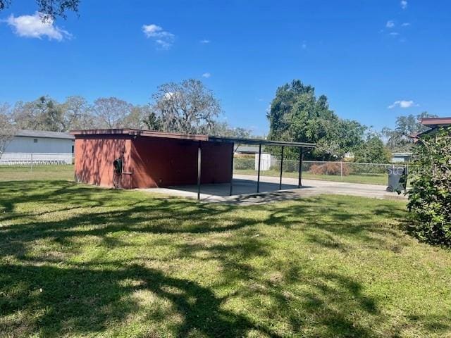 view of outbuilding featuring fence, a carport, and an outdoor structure