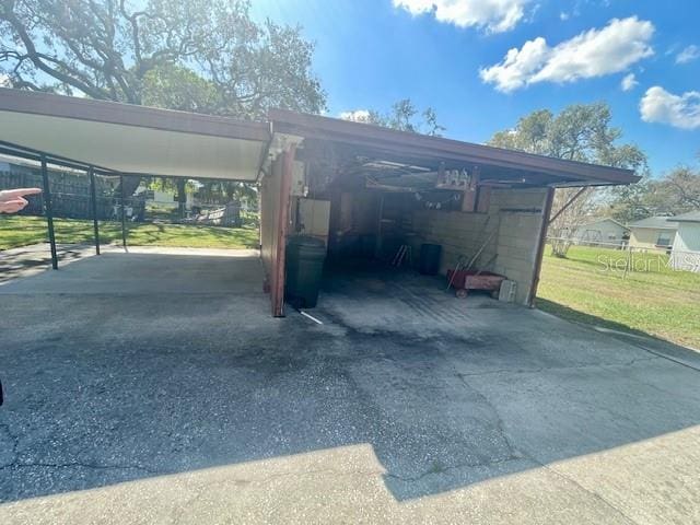 view of car parking with a carport, driveway, and fence