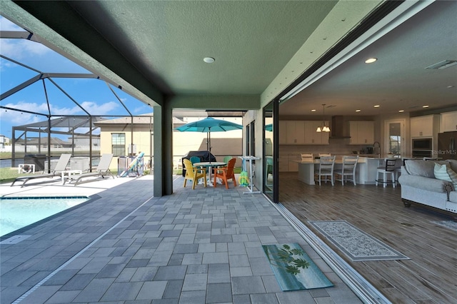 view of patio with visible vents, a fenced in pool, outdoor dry bar, a lanai, and a sink