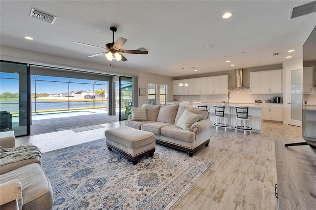 living room with recessed lighting, visible vents, a textured ceiling, and light wood finished floors