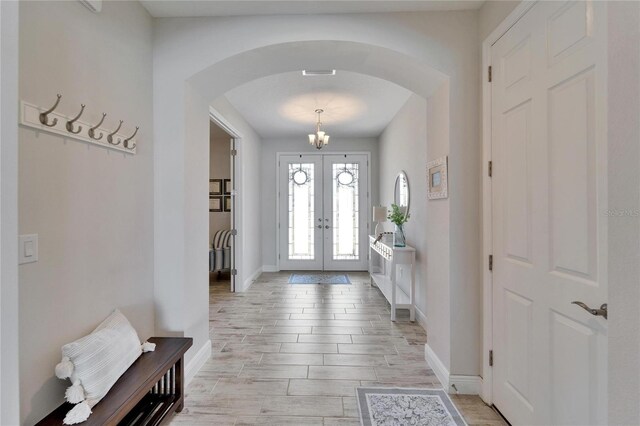 entryway featuring wood tiled floor, arched walkways, baseboards, and french doors